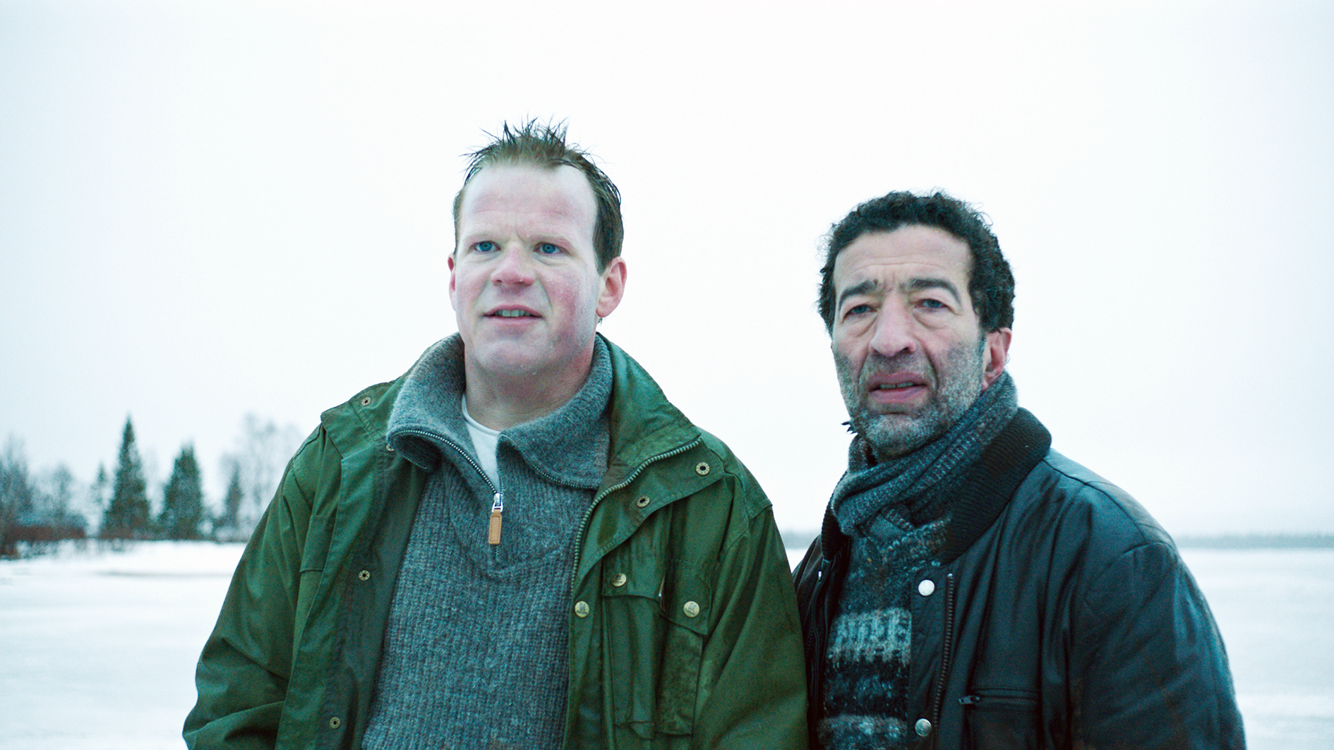Filmstill aus "Welcome to Norway": Zwei Männer stehen in einer Schneelandschaft und beobachten etwas außerhalb des Bildfeldes.