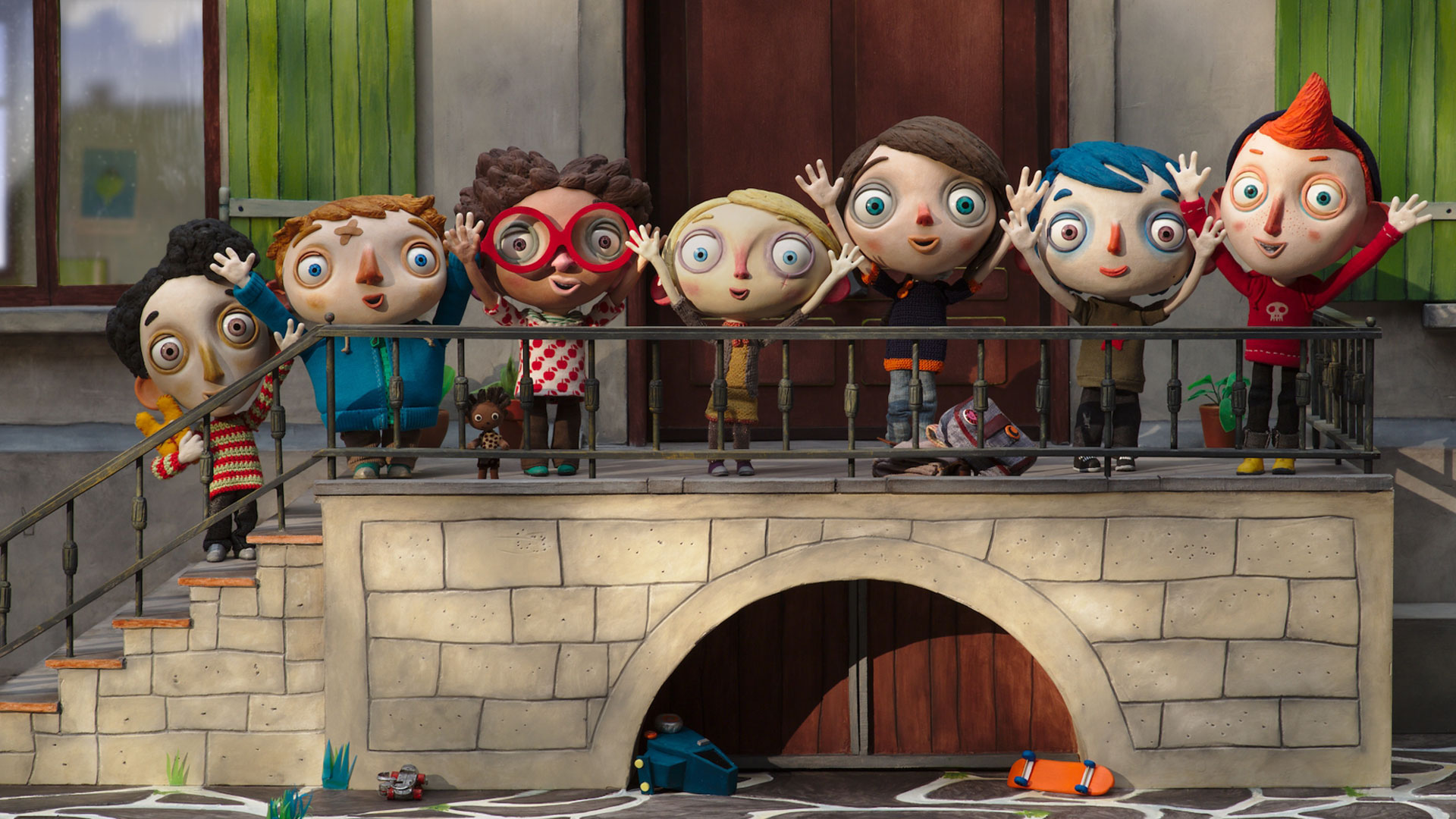 Filmstill aus dem Animationsfilm "Mein Leben als Zucchini": Sieben Kinder mit großen Köpfen und schmalen Körpern stehen an dem Geländer einer Steintreppe und reißen freudig die Arme in die Luft.