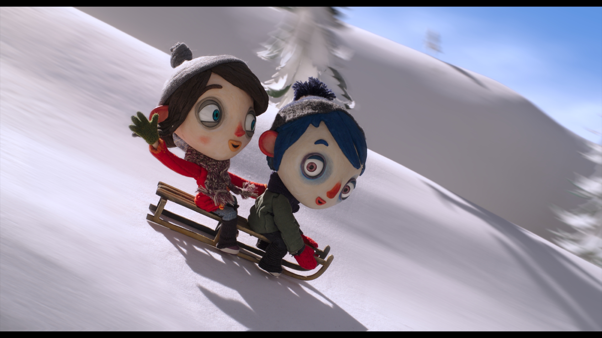 Der blauhaarige Junge Zucchini und seine Freundin Camille rodeln auf einem Holzschlitten freudig einen schneebedeckten Abhang hinunter.