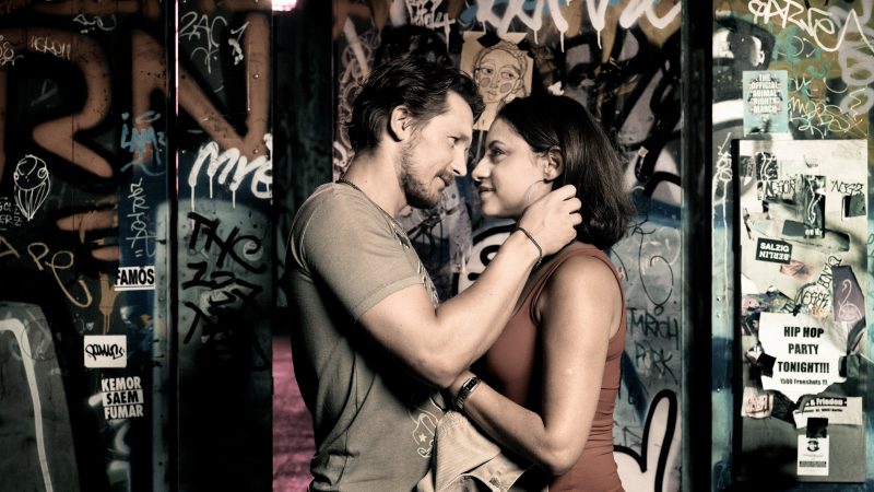 Filmstill von "Nur eine Frau": Ein inniges junges Paar vor einer mit Graffiti besprayten Metalltür.