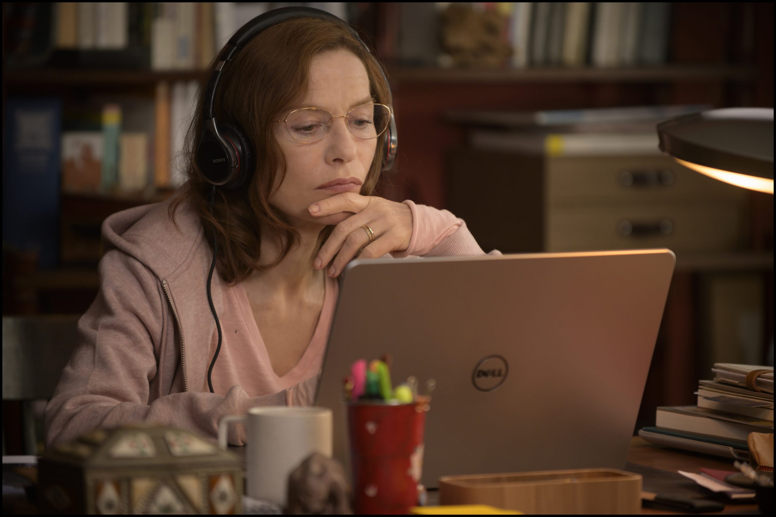 Eine Frau mittleren Alters sitzt mit Kopfhörern konzentriert an einem Laptop.